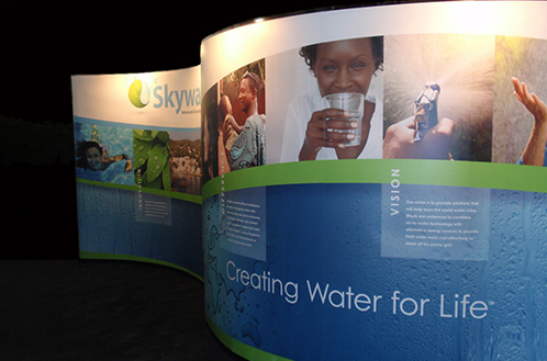 Skywater tradeshow exhibit featuring a branded display wall, large-format graphics, reception counter, brochure stand, and seating area.